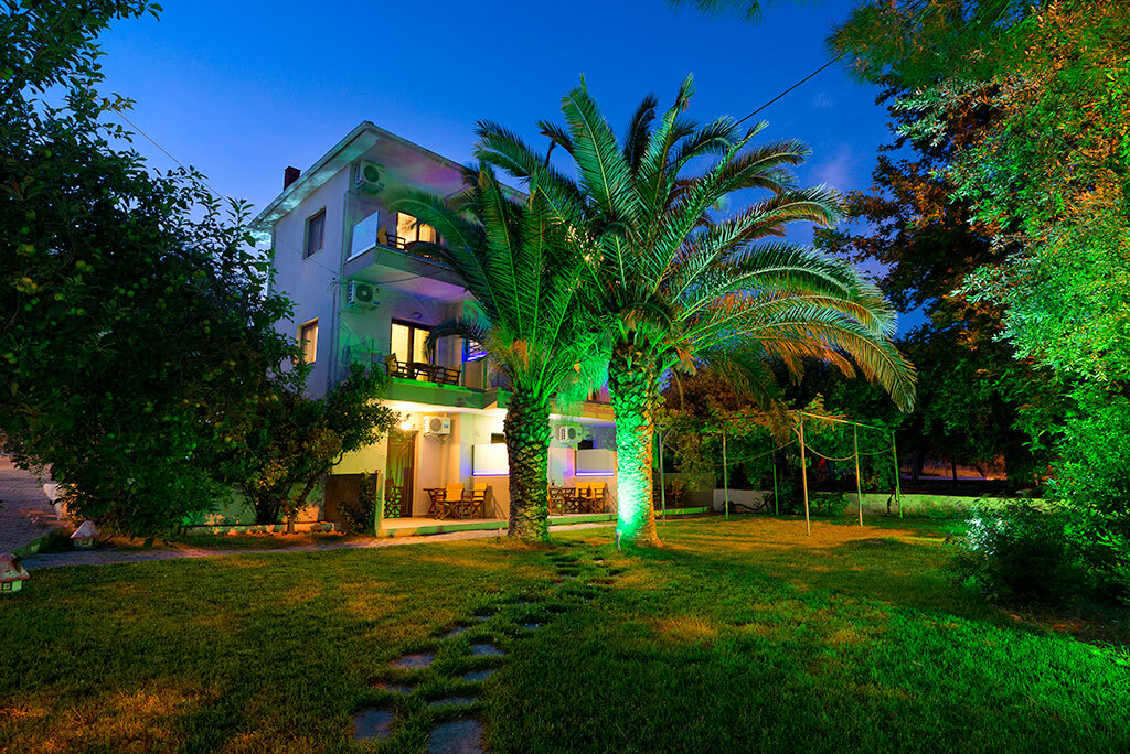 The estate and its great palm tree in the garden at dusk